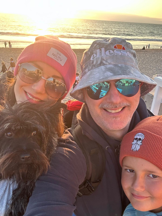Familie mit Hund am Strand bei Sonnenuntergang